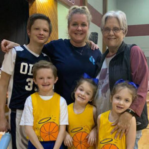 Debbie dReed stands with her daughter, Randi, and four grandchildren at a basketball game.