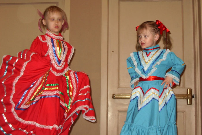 Two little girls wear Mexican dresses and perform dances.
