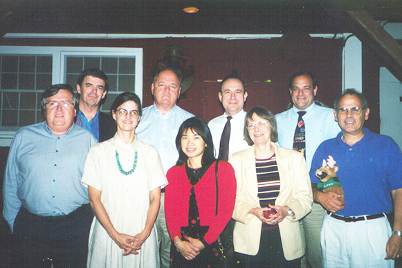 Six men and three women pose in two rows for a group shot.