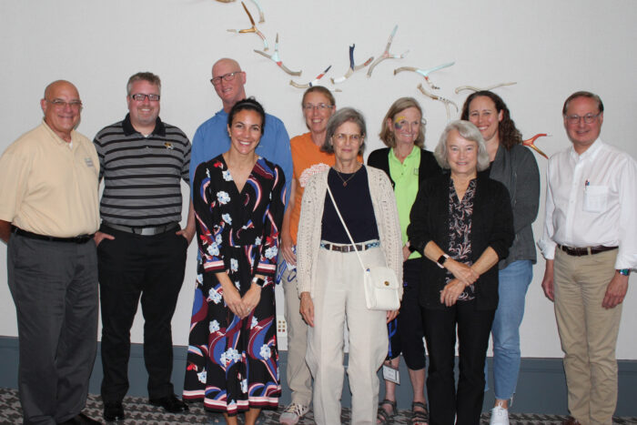 Six women and four men stand in two rows in a group shot.