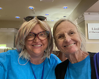 Two women in blue Hill Day shirts. One is wearing glasses.