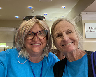 Two women in blue Hill Day shirts. One is wearing glasses.