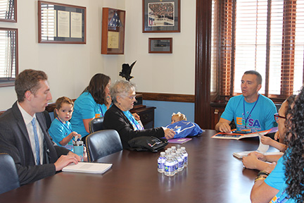 Advocates are sitting around a conference table sharing their stories with a staffer from a senator's office.
