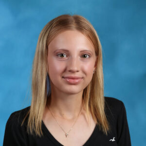 Photo of Nicole wearing a black shirt on a blue background.